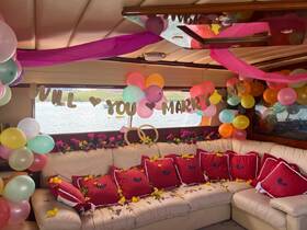 A beautifully decorated cabin on a boat, featuring colorful balloons and a romantic 'Will You Marry Me' banner, perfect for a proposal or special celebration.