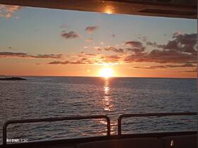 A stunning sunset view over the ocean from the deck of a boat, creating a serene and picturesque atmosphere perfect for evening cruises.