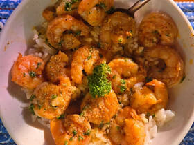 A delicious serving of shrimp over rice, garnished with parsley, showcasing the culinary delights available on board.