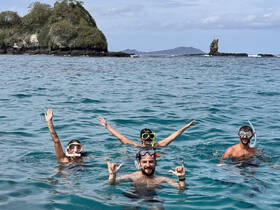 A lively group enjoys snorkeling in crystal-clear waters, showcasing the excitement of ocean adventures and island exploration.