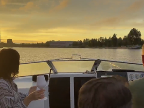 A couple enjoys drinks while cruising on a boat at sunset, creating a perfect atmosphere for relaxation and celebration on the water.