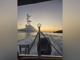 A scenic view from the back of a boat cruising at sunset, showcasing the tranquil waters and beautiful cloud formations.