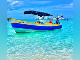 A vibrant boat named 'Niño Gael' is anchored in clear turquoise waters, with people onboard enjoying the beautiful day — a perfect scene for water adventures.