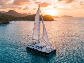 A stunning aerial view of a catamaran sailing through tranquil waters at sunset, showcasing the beauty of sailing adventures in picturesque landscapes.