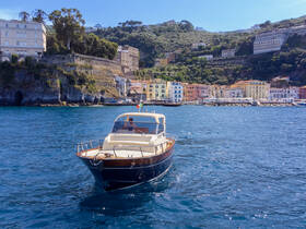 A stylish boat navigates the clear waters near a picturesque coastal town, showcasing the beauty of the Amalfi Coast.