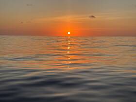 A serene sunset over calm waters, creating a picturesque backdrop for evening boat adventures.