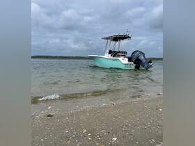 A sleek speedboat rests on the shore, showcasing its design against a backdrop of cloudy skies and calm waters — perfect for a day of adventure on the water.