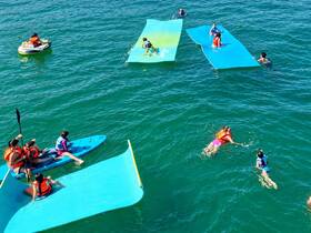 A lively scene of children and adults enjoying a day on the water, featuring paddleboarding and swimming activities — perfect for family fun in the sun.