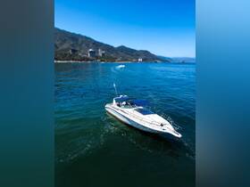 A stunning aerial view of a sleek speedboat cruising through clear waters, set against a backdrop of lush mountains and a vibrant coastline.