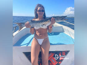 A joyful angler proudly displays her catch aboard a boat, showcasing the thrill of fishing on the open water.