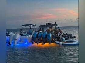 A lively group enjoys a sunset boating experience, engaging with jet skis and each other in shallow waters — perfect for a fun-filled day on the water.