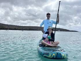 A family enjoys paddleboarding together in calm waters, creating lasting memories in a beautiful outdoor setting.