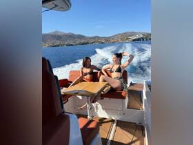 Two friends relax on a boat, enjoying the sunny weather and scenic views — a perfect moment for summer adventures on the water.