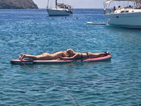 Two friends relax on a paddleboard in crystal-clear waters, enjoying a sunny day of fun and relaxation on the water.