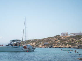 A lively scene featuring a group enjoying snorkeling and swimming near a boat in crystal-clear waters, set against a picturesque coastal backdrop.