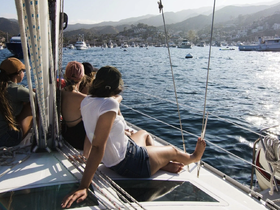 A group of friends enjoys a scenic sailing experience, relaxing on the deck while taking in the beautiful ocean views.