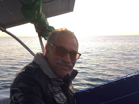 A man enjoys a serene moment on a boat, capturing the tranquil sea and sunset in the background — perfect for those seeking peaceful boating experiences.