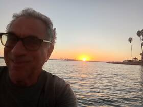 A joyful selfie captures a stunning sunset over the water, creating a perfect backdrop for memorable moments on a boating adventure.