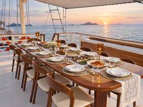 An elegantly set dining table on a boat, featuring a variety of delicious dishes and a stunning sunset backdrop — perfect for memorable dining experiences at sea.