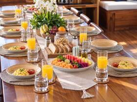 A beautifully arranged breakfast spread on a boat dining table, featuring fresh fruits, omelets, and refreshing drinks — perfect for a luxurious morning on the water.