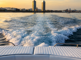 A stunning view from the back of a boat, showcasing the wake and city skyline at sunset — perfect for capturing the essence of a serene boating experience.