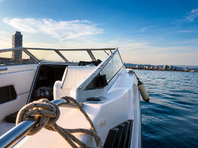 A sleek speedboat captured from the side, showcasing its elegant design against a backdrop of a vibrant city skyline and tranquil waters.