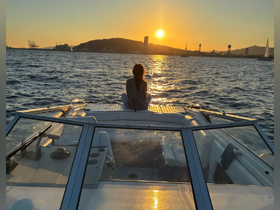 A serene sunset view from the back of a boat, where a woman enjoys the tranquil waters and golden hues of the evening sky — perfect for romantic getaways or peaceful retreats on the water.