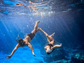 A couple enjoys snorkeling underwater, showcasing the vibrant marine life and crystal-clear waters — a perfect adventure for ocean lovers.