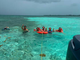 A lively group enjoys a fun day swimming and snorkeling in the crystal-clear waters, showcasing the perfect tropical getaway experience.