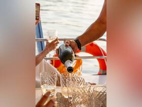 A hand pours champagne into elegant glasses on a boat, setting the scene for a luxurious celebration on the water.