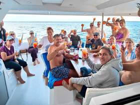 A lively group of guests aboard a boat raises their cocktails in celebration, capturing the essence of a fun-filled party on the water.