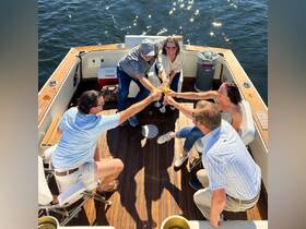 A lively group toasts with cocktails aboard a boat, celebrating together under the sun — perfect for memorable outings and gatherings on the water.