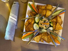 A beautifully arranged platter of appetizers featuring crispy chips, fresh vegetables, and a savory dip, perfect for enjoying on a boat trip.