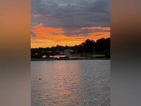 A stunning sunset casts vibrant colors over the water, creating a picturesque scene perfect for evening reflections and serene moments.