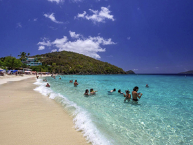 A vibrant beach scene with groups of people enjoying the clear turquoise waters, perfect for swimming and relaxation on a sunny day.