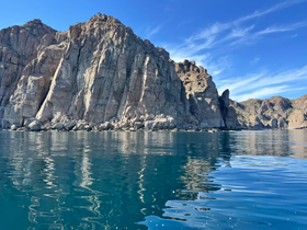 A stunning view of rocky cliffs reflecting in the calm waters, showcasing the natural beauty of the coastline — perfect for nature lovers and adventure seekers.