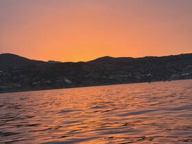 A stunning sunset over the water, casting vibrant hues across the surface, perfect for capturing the beauty of nature during a boating experience.