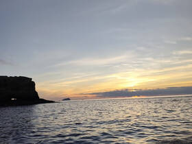 A stunning sunset over the tranquil waters, framed by a rocky coastline — a perfect backdrop for evening boat trips or romantic getaways.