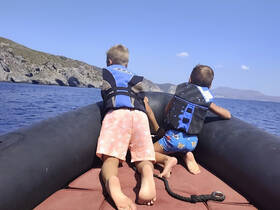 Two children enjoy an adventurous boat ride, gazing at the stunning coastal scenery — a perfect moment of exploration on the water.