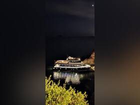 A stunning yacht docked at night, illuminated against the dark waters, showcasing its elegant design and serene surroundings.