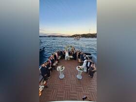 A beautiful wedding celebration takes place on the deck of a boat, surrounded by guests enjoying the scenic waterfront view.