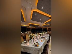 Elegant dining setup inside a boat, featuring beautifully arranged tables with floral centerpieces and gourmet dishes, perfect for upscale dining experiences on the water.