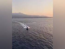 A stunning aerial view of a speedboat cruising through calm waters at sunset, showcasing the beauty of maritime adventures.