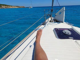 A relaxing moment on a sailboat, with a foot resting on the deck while enjoying the stunning turquoise waters — perfect for sailing enthusiasts.