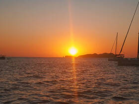 A stunning sunset view over the water, featuring sailboats silhouetted against the vibrant sky — perfect for capturing the essence of serene boating experiences.