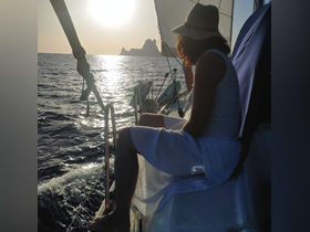 A serene moment captured at sunset on a sailboat, showcasing a guest enjoying the tranquil waters and stunning views — perfect for sailing enthusiasts.