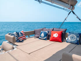 A cozy lounge area on a boat featuring comfortable seating and nautical-themed cushions, perfect for relaxing while enjoying the ocean views.