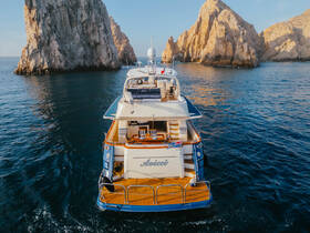 A stunning aerial view of a luxurious yacht named 'Avicii' anchored near dramatic rock formations, showcasing the beauty of the coastline.