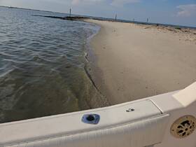 A view of a sandy shoreline and water, with the edge of a boat visible. The image lacks clarity and detail.