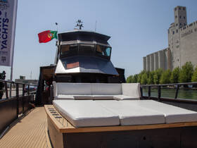 A sleek yacht docked with a spacious sunbathing area, showcasing a vibrant Portuguese flag. Ideal for luxury charters and waterfront events.